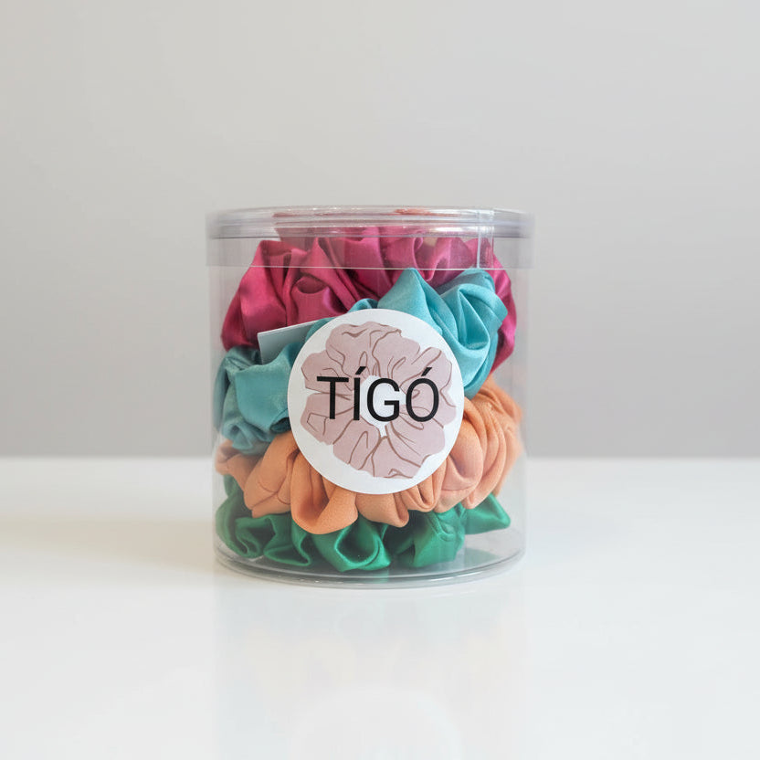Clear container with colorful scrunchies and a Tigó label on a white background